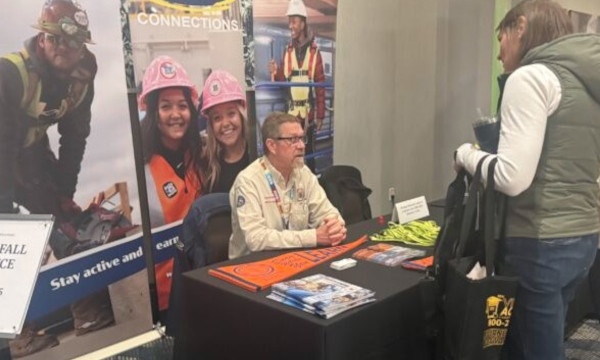 Conference attendees speaking with an exhibitor about school resources.