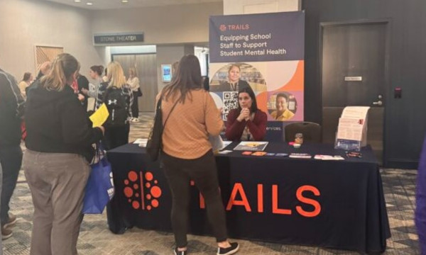 Conference attendees speaking with an exhibitor about school counseling resources.