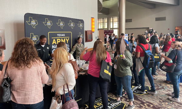 Texas Army National Guard exhibitor booth speaking with school counselors at a busy conference exhibit hall.