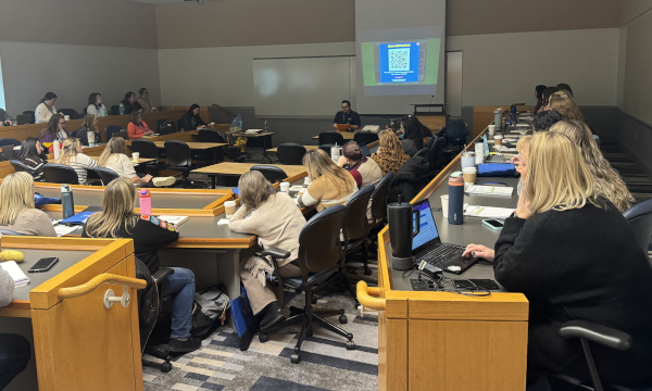 groups sitting at desks listening to a speaker