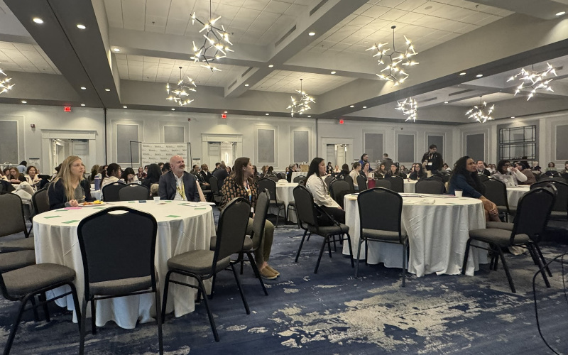 Ballroom filled with round tables and people sitting at the tables