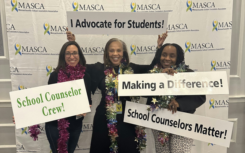 3 school counselors holding up school counselor signage