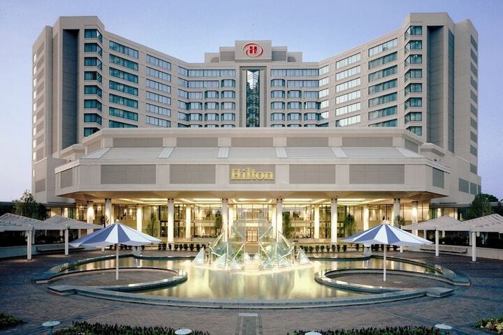 The outside of a Hilton hotel with a large water fountain in the front