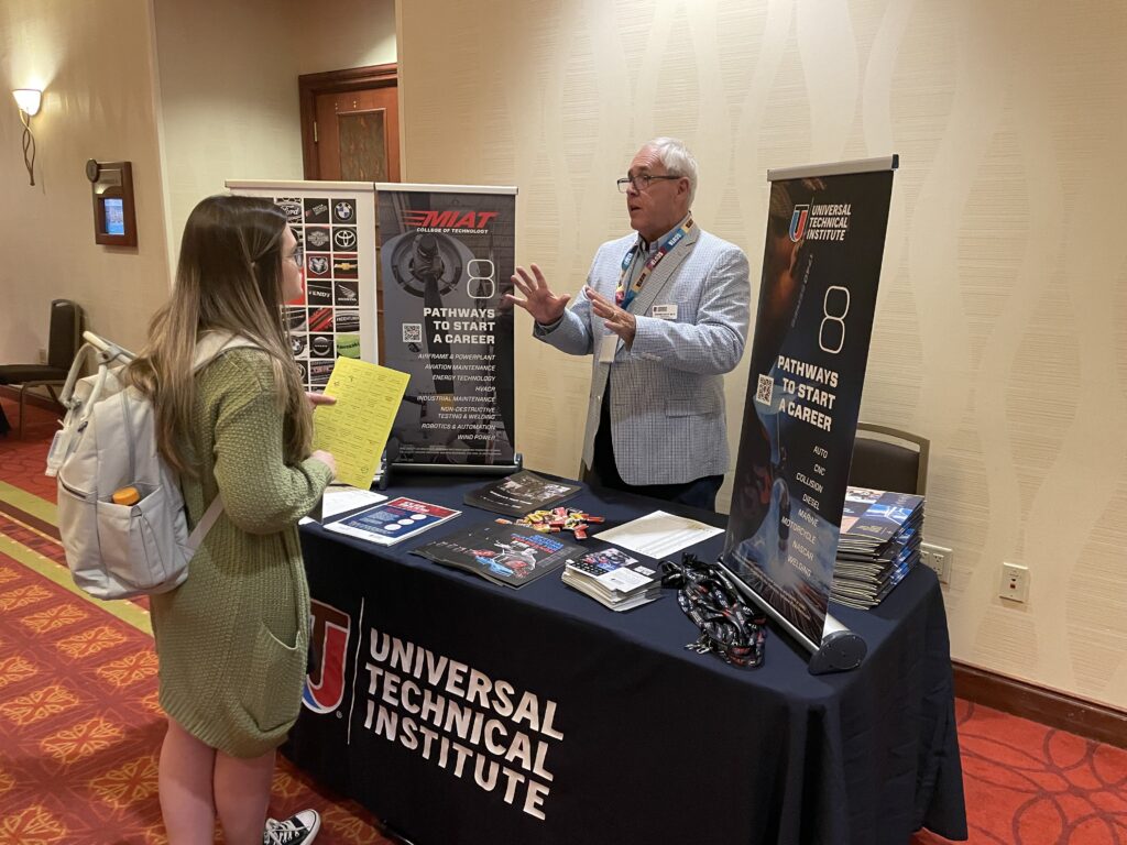 Exhibitor speaking with a conference attendee at the Southeast School Counselor and Administrator Leadership Institute.